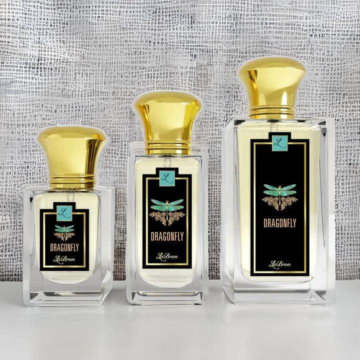 Three sizes of the Dragonfly fragrances laid out in a line with a white, mesh background. The label shows a blue dragonfly with a black background with "Labron" on their label.