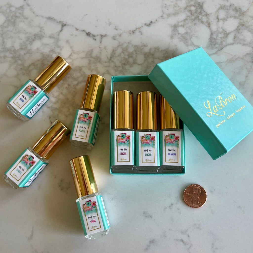 LaBron Perfume "Find Me" Sample Set; with your choice of Three or Six 5 ml Sprays. The box that comes with the products are in a white box with gold lettering for the label. The background is a white marble look that brings it all together.
