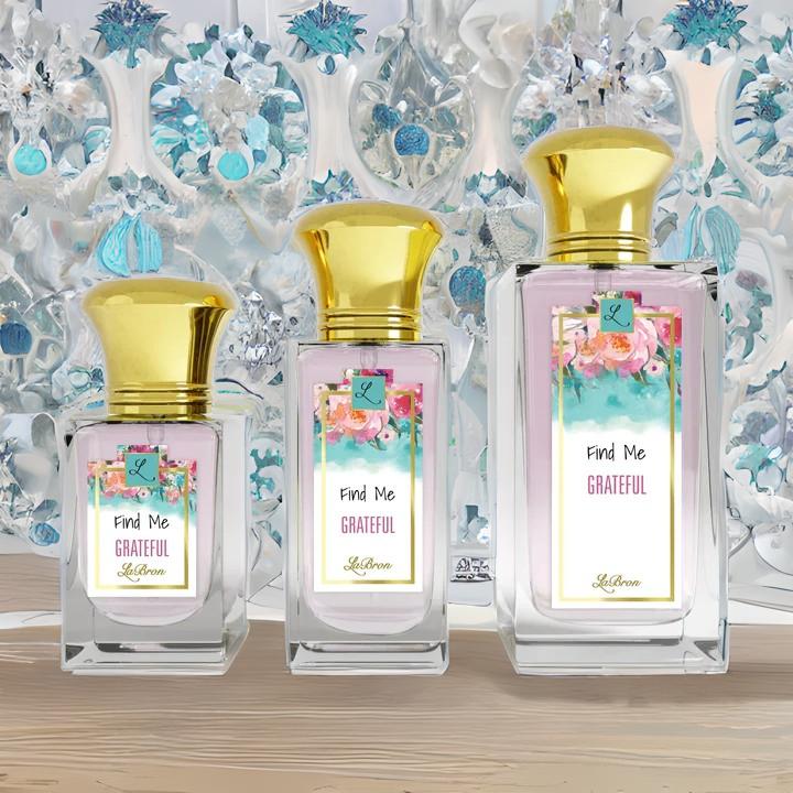 Find me "Grateful" products showcased in a line. This products shows a floral like background on their label and gold cap. The background of the image is surrounded by a glass like blue background.