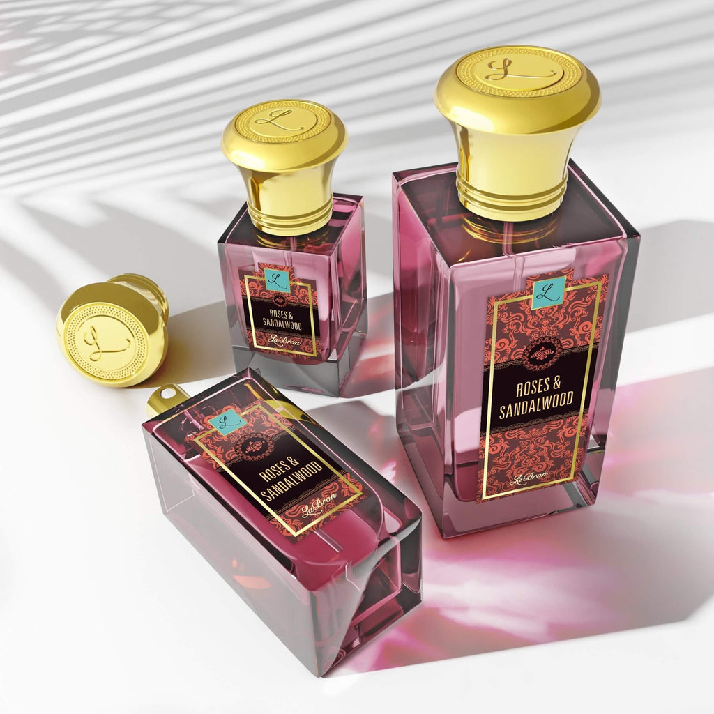 Three Roses & Sandalwood products are showcased and photo was taken at a higher angle. The products are shown with shadows and this product shows a red hue and moroccan style on their label and gold cap.